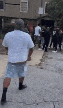 a man in a white shirt and shorts is standing in front of a crowd of people