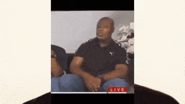 a man is sitting on a couch talking to another man .