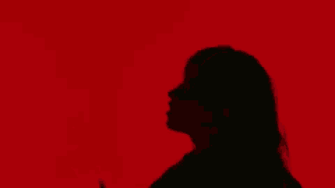 it is a silhouette of a woman making a peace sign with her hand .