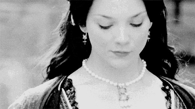 a black and white photo of a woman wearing a pearl necklace with the letter b on it