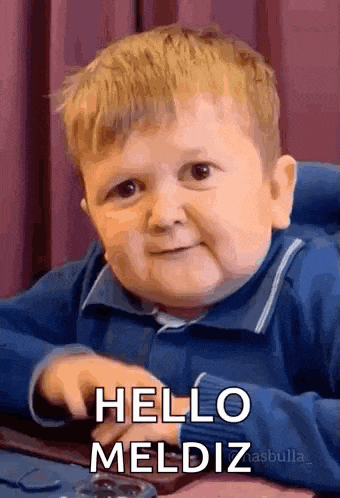a little boy is sitting at a table and making a funny face and saying hello .