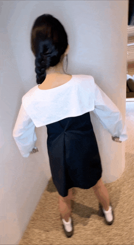 the back of a woman wearing a black dress and white sleeves
