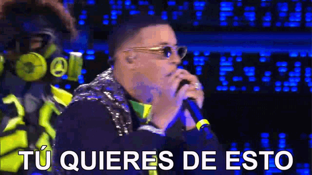 a man singing into a microphone with the words " tu quieres de esto " written below him