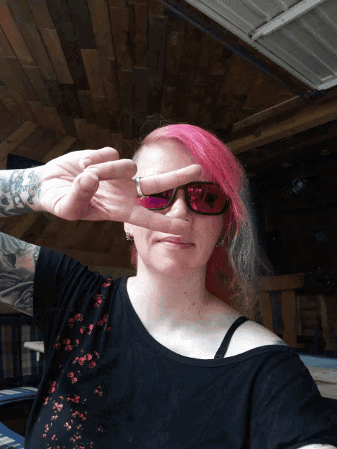 a woman with pink hair making a peace sign with her hands