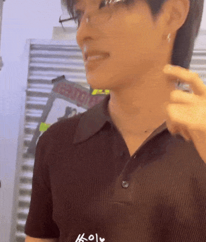 a man wearing glasses and a brown shirt is standing in front of a ladder that says reading