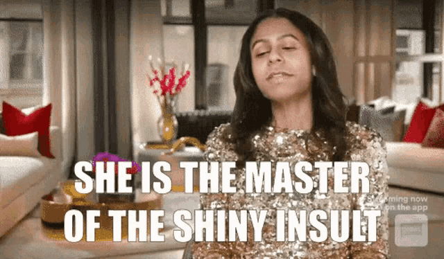 a woman in a gold sequined dress is sitting in a living room and says she is the master of the shiny insult .