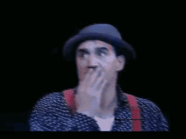 a man wearing a hat and suspenders covering his mouth
