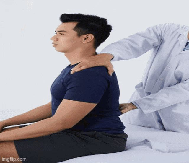 a man in a blue shirt is getting a massage from a doctor in a white coat