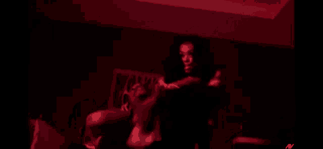 a woman is standing next to a man in a dark room with red lights .