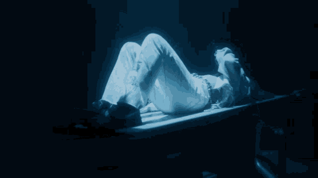a woman laying on her stomach in a dark room