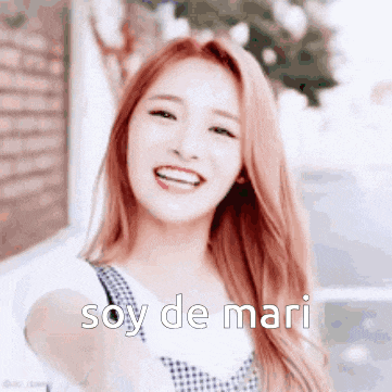 a woman with red hair is smiling with the words soy de mari written on the bottom of her face .