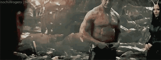 a shirtless man is standing next to a woman in a cave .