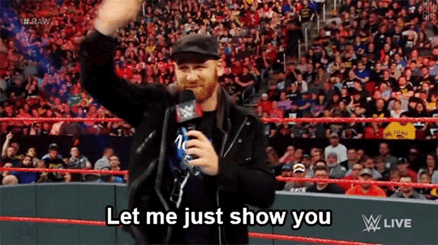 a man in a wrestling ring is holding a microphone and says let me just show you