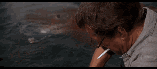 a man smoking a cigarette in front of a shark in the water