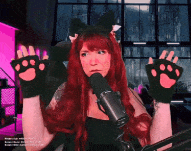 a woman with red hair is wearing cat paw gloves and a cat ear headband