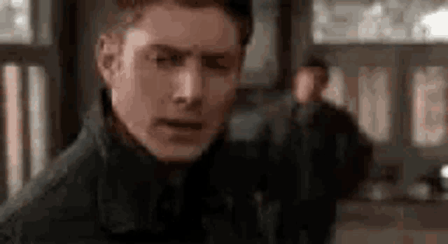 a close up of a man 's face with a blurry background of another man .
