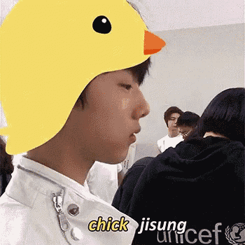 a young man wearing a yellow duck hat with the words `` chick jisung unicef '' written on it .