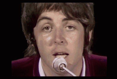 a close up of a man singing into a microphone with his mouth open
