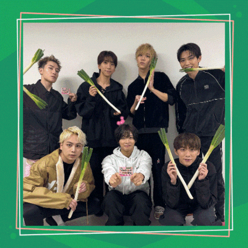 a group of young men are posing for a picture while holding green onions in their mouths