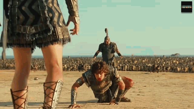 a scene from a movie shows a man kneeling on the ground while another man stands behind him