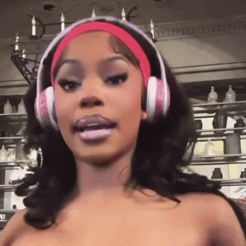a woman wearing pink headphones and a pink headband looks at the camera