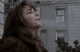 a woman in a fur coat is standing in front of a building with her eyes closed .