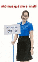 a woman in a blue shirt and black skirt is holding a sign on a stick .