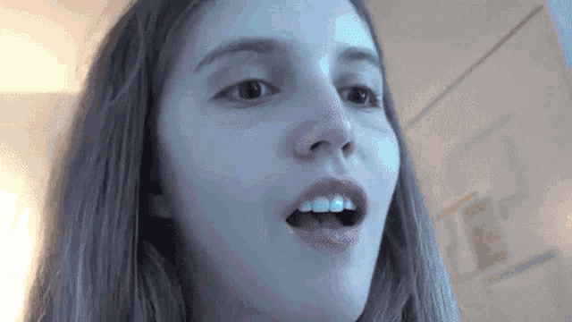 a close up of a woman 's face with her mouth open and her teeth visible .