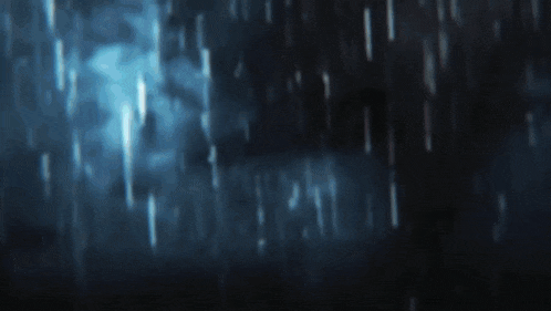 a blurry picture of rain falling on a dark background .