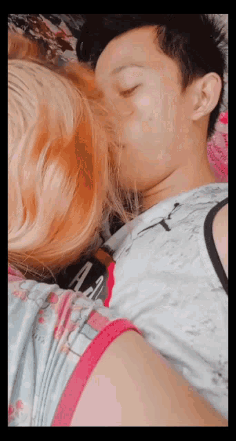 a man and a woman are laying on a bed and the woman is wearing a shirt that says a.a.