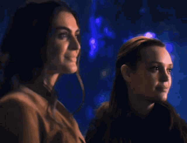 two women are standing next to each other and smiling