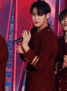 a man in a red jacket is holding a microphone in his right hand
