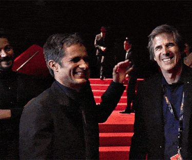 a man in a suit and a blue shirt is shaking hands with another man