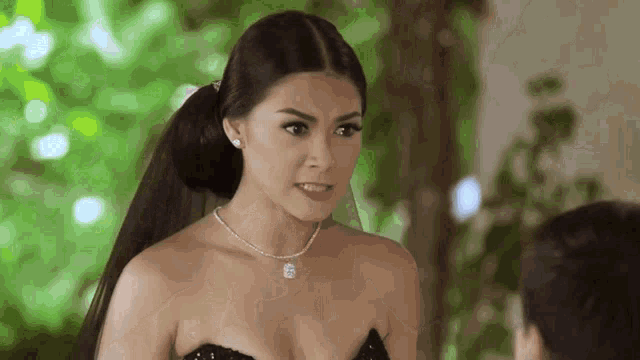 a woman in a black dress with a veil on her head looks at a man
