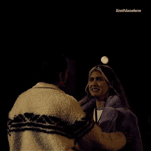 a woman in a purple coat is crying while a man in a white jacket hugs her