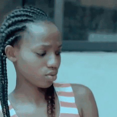 a young woman with braids in her hair is wearing a striped tank top and looking at the camera .
