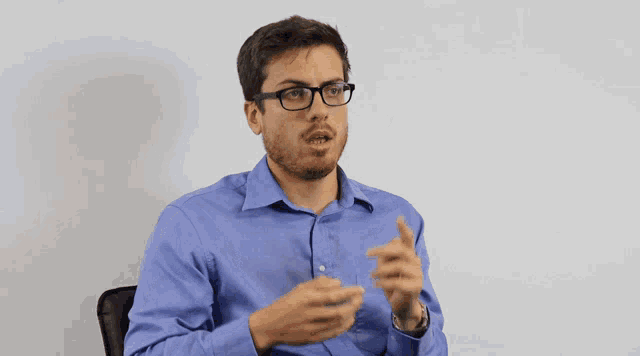 a man wearing glasses and a blue shirt talks