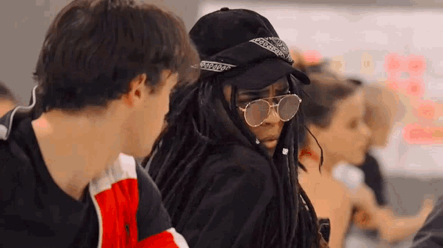 a woman with dreadlocks wearing sunglasses and a baseball cap