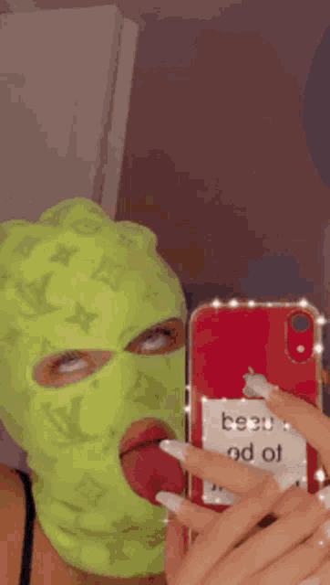 a woman wearing a ski mask is taking a picture of herself with her tongue out .