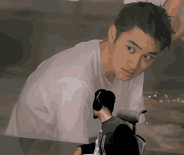 a man in a white shirt is looking at a man in a black shirt