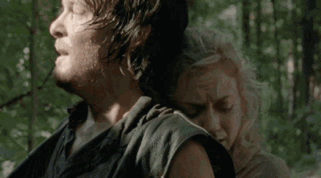a man is carrying a woman on his shoulders in the woods