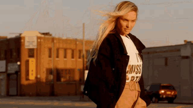a woman wearing a t-shirt that says " i miss you " walks down the street
