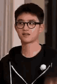 a close up of a young man wearing glasses and a black shirt .