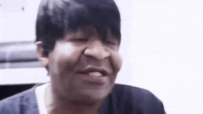 a man with short black hair is making a funny face while looking at the camera .
