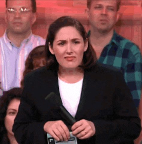 a woman in a suit holds a microphone in front of a crowd with the letter c on it
