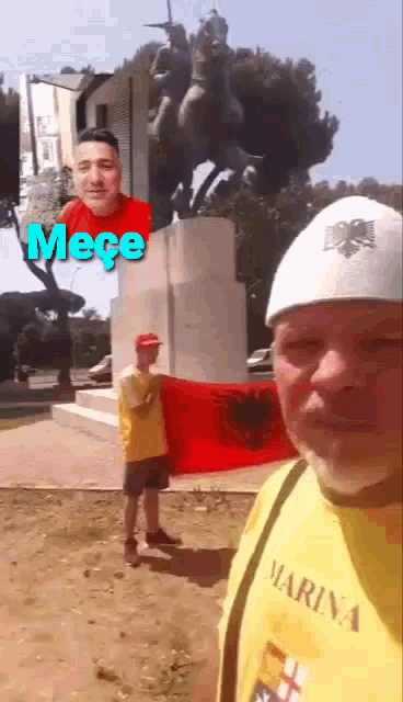 a man in a marina shirt holds a flag in front of a monument