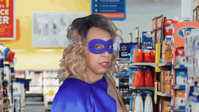 a woman wearing a blue cape and mask stands in a store