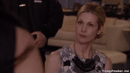 a woman wearing a necklace is sitting in front of a man holding a hat .