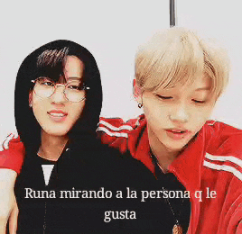 two young men are standing next to each other with the words runa mirando a la persona q le gusta on the bottom .
