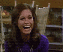 a woman in a purple shirt is laughing in front of a table and chairs .